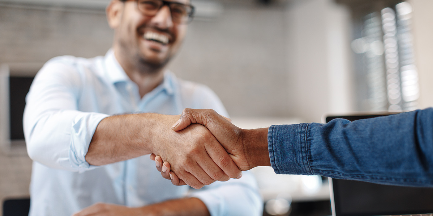 Two people shaking hands over a desk