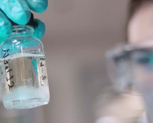 A woman examining a container of liquid.